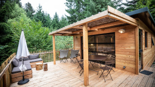Terraza de madera en Chalet Toronto con asientos, sombrilla y rodeada de exuberantes árboles verdes.