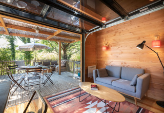 Binnen-buiten leefruimte van Chalet Toronto, Village Huttopia Pays de Condrieu, Frankrijk, met houten afwerking.