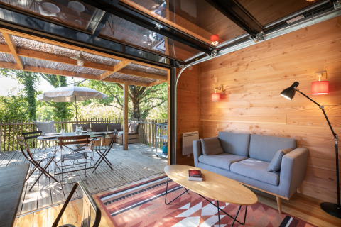 Wohnbereich im Chalet Toronto, Village Huttopia Pays de Condrieu, Frankreich, mit Holzverkleidung und Terrasse.