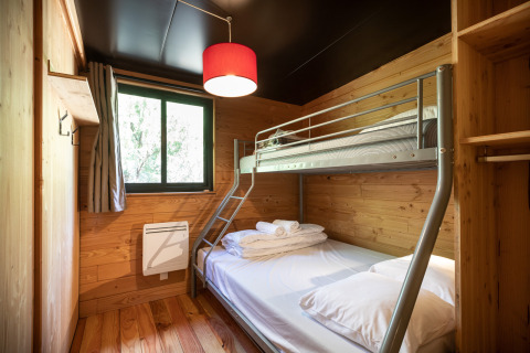 Værelse med køjeseng og træinteriør på Chalet Toronto, Village Huttopia Pays de Condrieu i Frankrig.