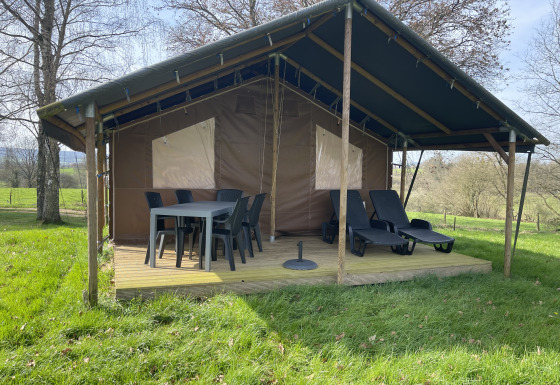 Lodge en plein air avec terrasse couverte, table, chaises et transats au Camping La Colline en Belgique.