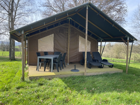 Outdoor-Lodge mit überdachter Terrasse, Esstisch, Stühlen und Liegen auf Camping La Colline in Belgien.