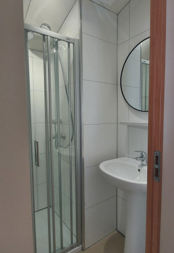 Bagno moderno con box doccia, lavabo e specchio rotondo al Beach House presso Beloofde Land, Paesi Bassi.