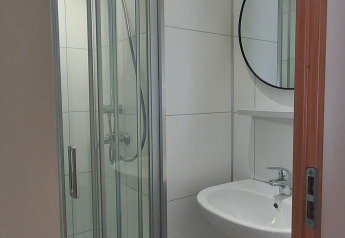 Baño moderno con cabina de ducha, lavabo y espejo redondo en Beach House en Beloofde Land, Países Bajos.