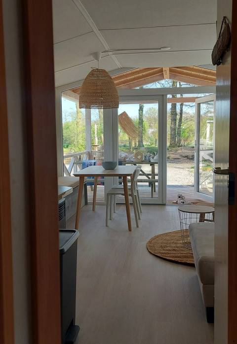 Helles Strandhausinterieur mit Esstisch, Stühlen und Terrasse mit Naturblick im Beloofde Land in den Niederlanden.