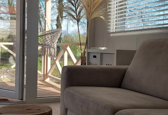 Sunlit living room in Beach House at Beloofde Land, Netherlands, with view of terrace and greenery outside.
