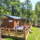Familie nyder en solrig dag på terrassen ved en hytte i Veluwecamping De Pampel i Holland.