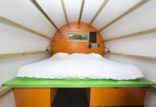 Interior view of a cozy cabin called 'Sleeping in a tree trunk' at Veluwecamping De Pampel, Netherlands.