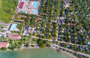 Vista aérea de SunLodge Katsura en Camping Gasparina, Italia, con piscinas, árboles y zona junto al lago.