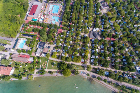 Vue aérienne du SunLodge Katsura au Camping Gasparina en Italie, avec piscines, arbres et bord du lac.