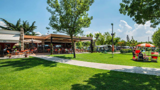 Buitenruimte bij SunLodge Katsura op Camping Gasparina in Italië met groene grasvelden en terrasstoelen.