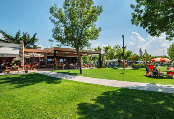 Zona exterior en SunLodge Katsura de Camping Gasparina en Italia, con césped verde y terraza soleada.