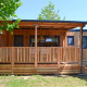 SunLodge Sabai, een moderne houten lodge met overdekte veranda bij Camping Gasparina in Italië, omgeven door natuur.