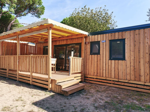 Vista exterior de SunLodge Sabai en Camping Gasparina, Italia, con revestimiento de madera y terraza cubierta.