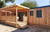 Vista exterior de SunLodge Sabai en Camping Gasparina, Italia, con revestimiento de madera y terraza cubierta.