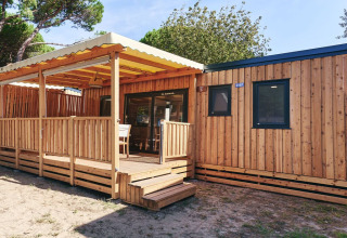 Vista exterior de SunLodge Sabai en Camping Gasparina, Italia, con revestimiento de madera y terraza cubierta.