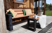 Banco de madera con cojines y mesa en la terraza de Ackerlodge, Ackerlodges Ruinerwold BV, Países Bajos.
