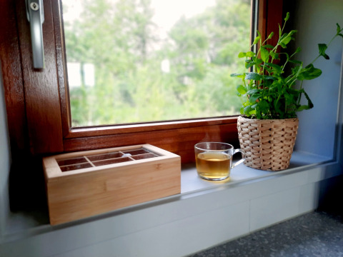 Rebord de fenêtre à Ackerlodge, Ruinerwold BV, avec tasse de thé, boîte en bois et plante en pot.