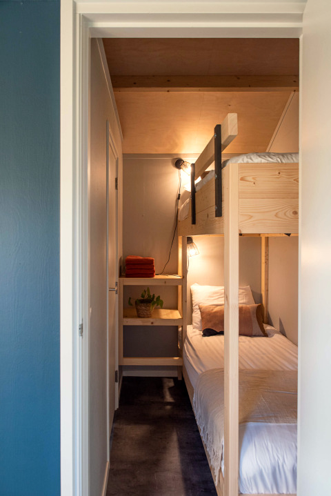Chambre étroite avec lits superposés en bois, linge blanc et étagère à Ackerlodge, Pays-Bas.