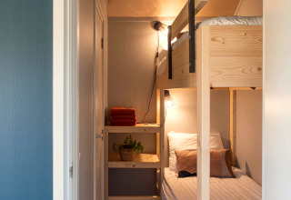 Chambre étroite avec lits superposés en bois, linge blanc et étagère à Ackerlodge, Pays-Bas.