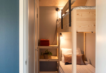 Smalle kamer met houten stapelbed, witte lakens en wandplank bij Ackerlodge, Ruinerwold, Nederland.