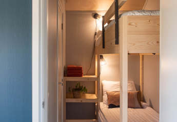 Dormitorio estrecho con literas de madera, ropa de cama blanca y estantería en Ackerlodge, Países Bajos.
