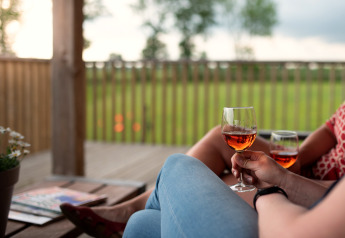 Twee mensen genieten van een glas rosé op het terras van Ackerlodge, Ruinerwold, Nederland.