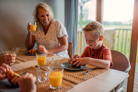 Famille prenant le petit-déjeuner avec croissants et jus d'orange à Ackerlodge d'Ackerlodges Ruinerwold BV, Pays-Bas.