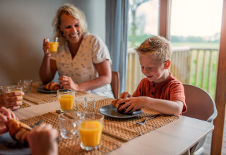 Famille prenant le petit-déjeuner avec croissants et jus d'orange à Ackerlodge d'Ackerlodges Ruinerwold BV, Pays-Bas.