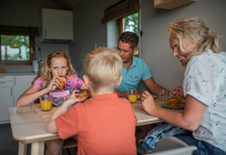Familia desayunando croissants y jugo de naranja en la cocina de Ackerlodge, Ackerlodges Ruinerwold BV, Países Bajos.