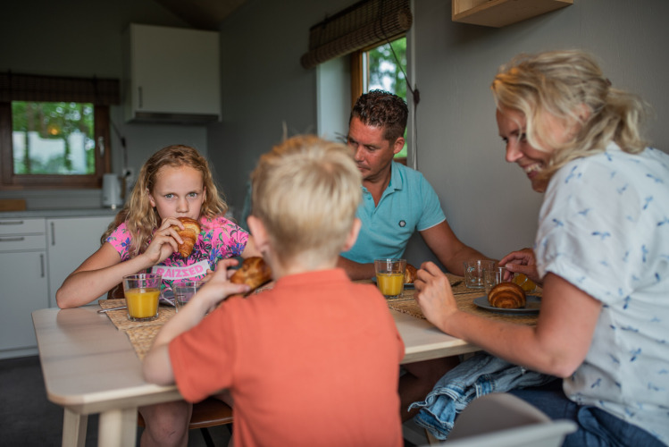 Familia desayunando croissants y jugo de naranja en la cocina de Ackerlodge, Ackerlodges Ruinerwold BV, Países Bajos.