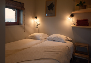 Knusse tweepersoonskamer in Ackerlodge bij Ackerlodges Ruinerwold BV, Nederland, sfeervol verlicht.