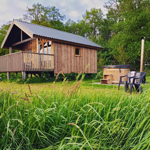 Houten lodge met veranda en buitenbad in groene omgeving bij Ackerlodges Ruinerwold, Drenthe, Nederland.