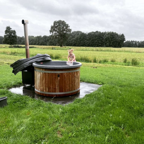 Ein kleines Kind sitzt in einem Outdoor-Whirlpool bei Ackerlodges Ruinerwold BV im Drenthe, Niederlande.
