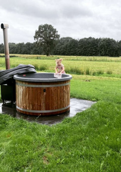 Un niño pequeño juega en una bañera de hidromasaje exterior en Ackerlodges Ruinerwold BV en Drenthe, Países Bajos.