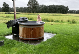 Ein kleines Kind sitzt in einem Outdoor-Whirlpool bei Ackerlodges Ruinerwold BV im Drenthe, Niederlande.