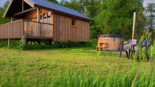 Cabaña de madera con veranda y jacuzzi exterior en Ackerlodges Ruinerwold BV, parque vacacional en Drenthe, Países Bajos.
