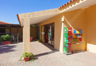 Ingresso di Camping Gasparina in Veneto, Italia, con espositori all’aperto e piccoli tavoli all’esterno.