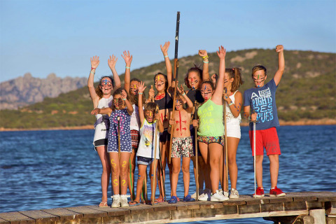 Niños con pintura facial celebran en un muelle junto al agua durante unas vacaciones de glamping.