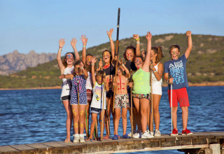 Bambini con il viso dipinto festeggiano su un molo d’acqua in un campeggio glamping.