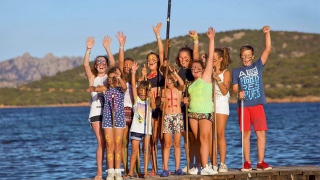 Niños con pintura facial celebran en un muelle junto al agua durante unas vacaciones de glamping.