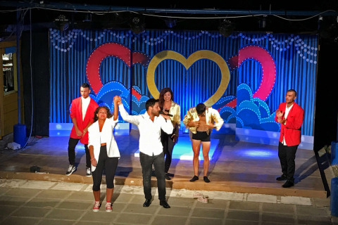 Espectáculo nocturno en un parque de vacaciones con artistas en el escenario aplaudiendo tras la actuación.