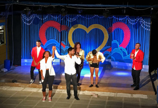 Spectacle du soir dans un parc de vacances avec des artistes qui applaudissent et saluent sur scène.