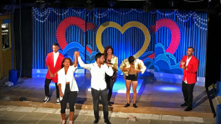 Espectáculo nocturno en un parque de vacaciones con artistas en el escenario aplaudiendo tras la actuación.