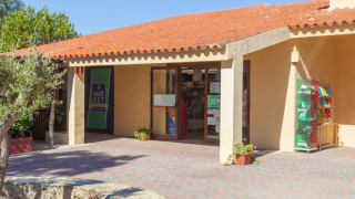 Entrada a un mercado en un parque vacacional en un día soleado con techo de tejas, ambiente glamping.