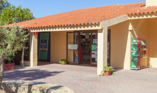 Entrada a un mercado en un parque vacacional en un día soleado con techo de tejas, ambiente glamping.