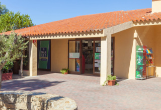 Entrée d'un marché dans un parc de vacances, toit en tuiles, journée ensoleillée, ambiance glamping.