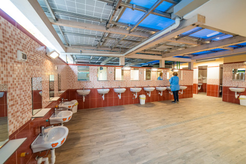 Baño comunitario amplio con varios lavabos y espejos en un parque de vacaciones de glamping moderno.