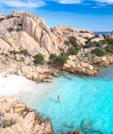 Aguas turquesas y formaciones rocosas cerca de Palau, Cerdeña, Italia, con una persona nadando y gaviotas.