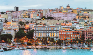 Vista de edificios coloridos y puerto deportivo junto al mar en Palau, Cerdeña, Italia, con arquitectura histórica.